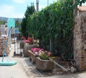 Un aro de baloncesto está en un jardín al lado de un muro de piedra.