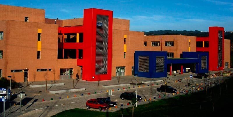 Un gran edificio rojo y azul con coches aparcados delante.