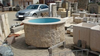 Un coche está aparcado delante de un gran pozo de piedra.