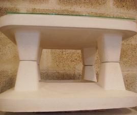 Una mesa blanca con tapa de cristal está situada delante de una pared de ladrillos.