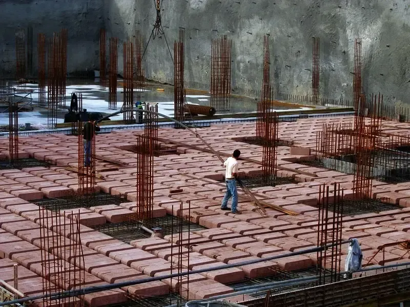 Un hombre está parado sobre un piso de ladrillos en un sitio de construcción.