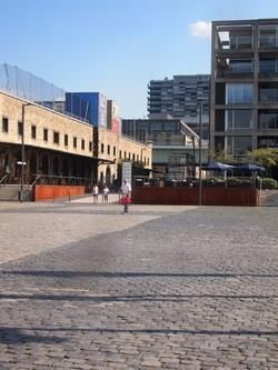 Ein Mann geht eine Kopfsteinpflasterstraße vor einem großen Gebäude entlang.