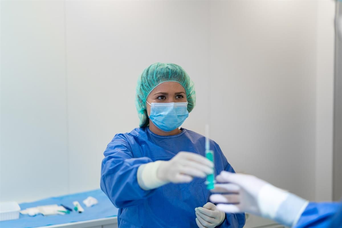 Ein Chirurg mit Maske und Handschuhen hält eine Spritze.