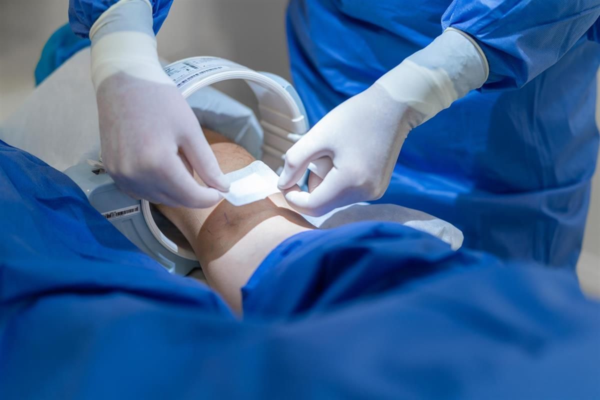 Ein Chirurg legt einem Patienten einen Verband am Arm an.