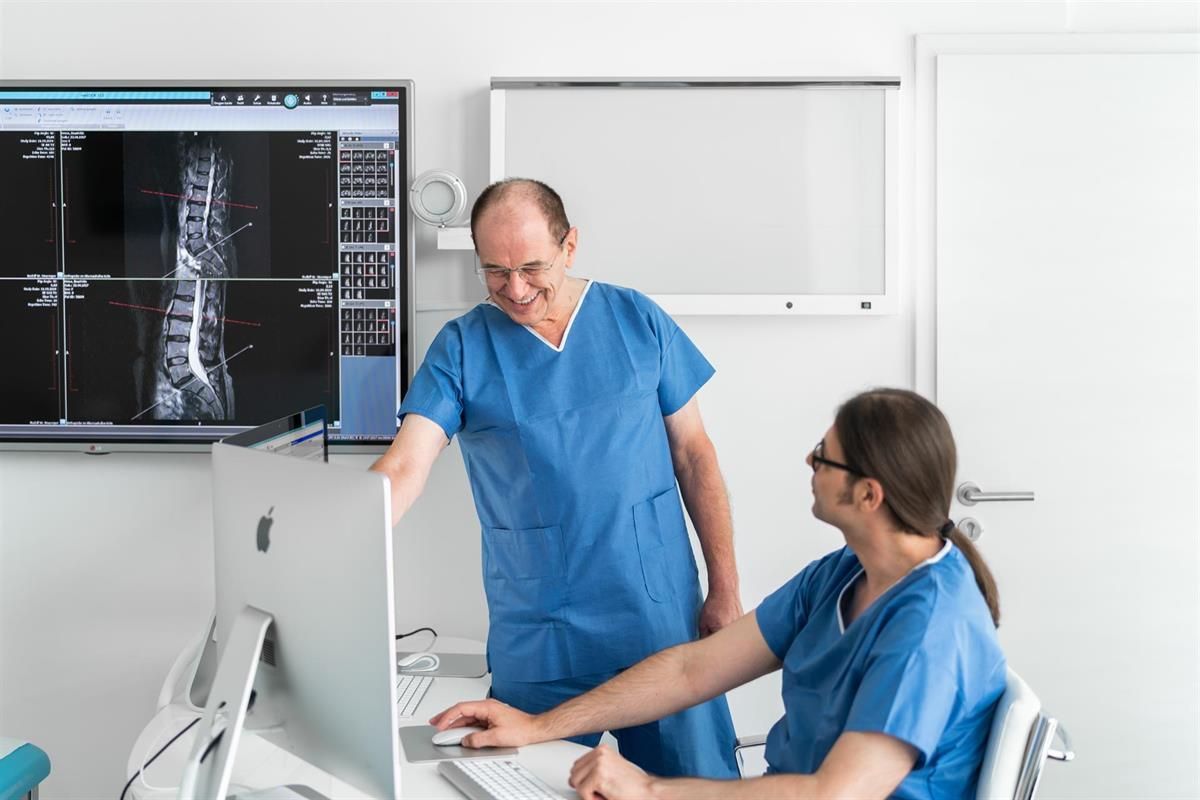 Zwei Ärzte betrachten eine Röntgenaufnahme auf einem Computerbildschirm.