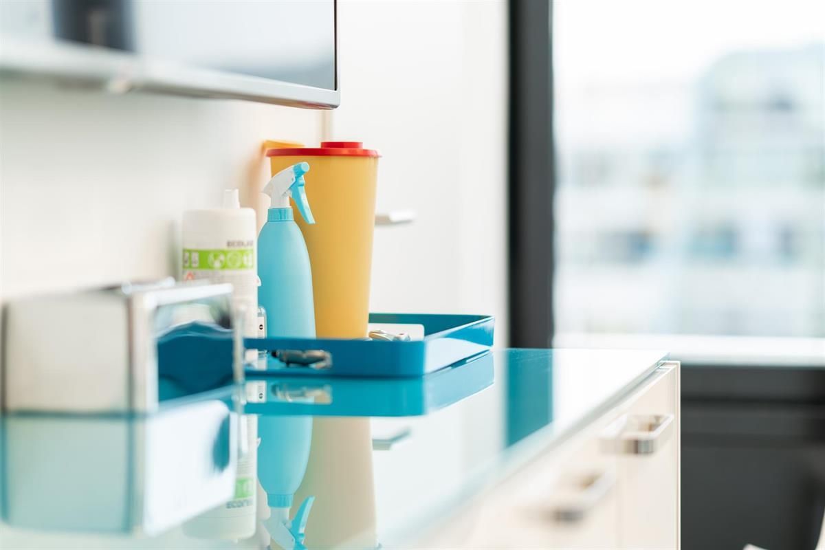 Auf einer Theke neben einem Fenster steht ein Tablett mit einer Sprühflasche.