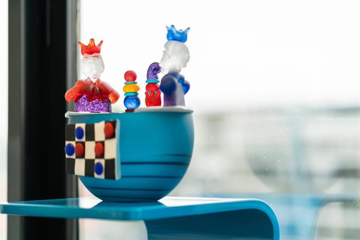 Eine blaue Schüssel mit einem Schachspiel darin auf einem blauen Tisch.