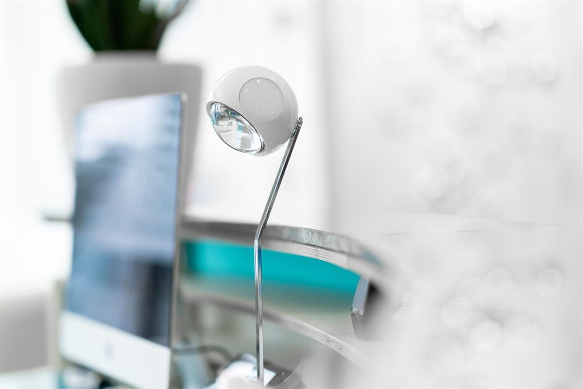 Auf einem Schreibtisch neben einem Computer steht eine Lampe.