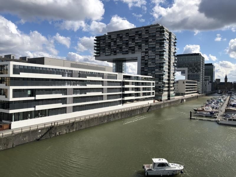 Vor einem großen Gebäude neben einem Gewässer schwimmt ein Boot.