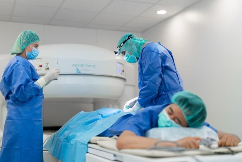 Zwei Chirurgen arbeiten in einem Krankenhauszimmer an einem Patienten.