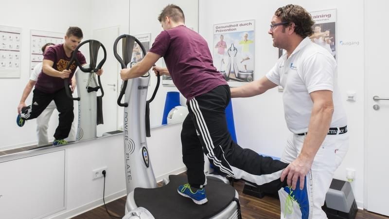 Ein Mann hilft einem Jungen auf einem Laufband in einem Fitnessstudio.