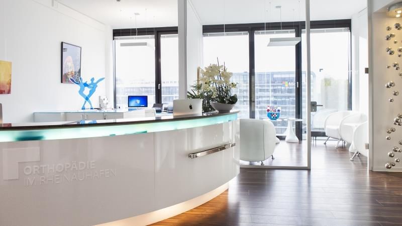 Ein Empfangstresen in einer Zahnarztpraxis mit vielen Fenstern.