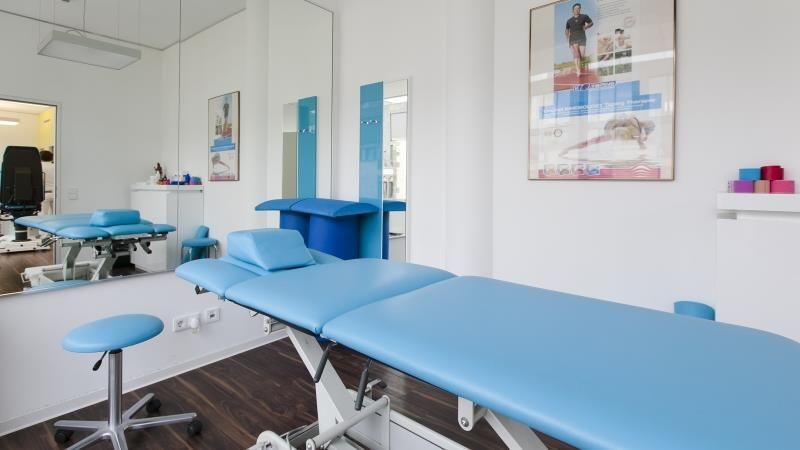 In einem Zimmer steht ein blaues Sofa mit einem Spiegel und einem Bild an der Wand.