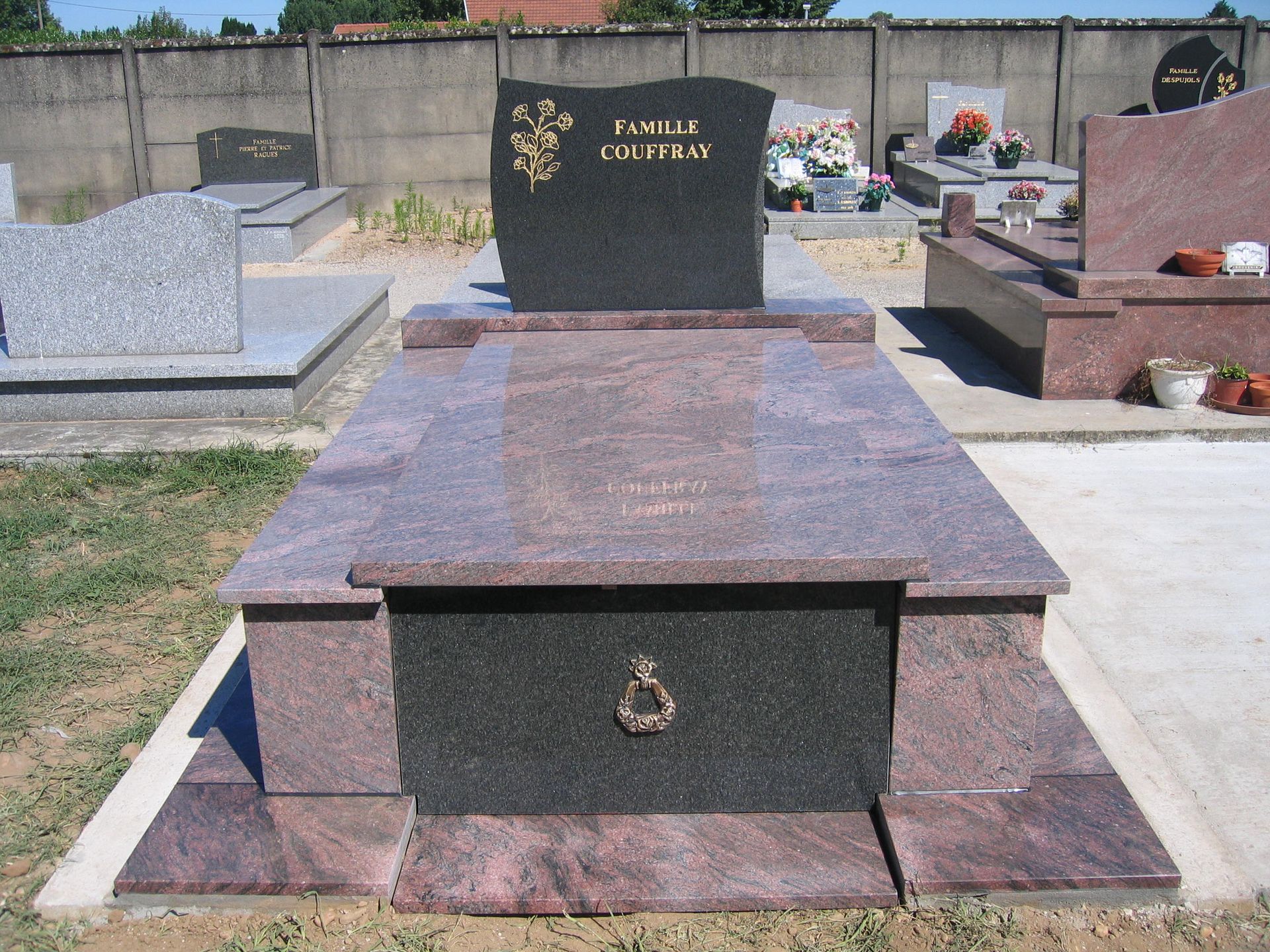 Pierre tombale dans un cimetière avec pierre tombale noire, granit rose/rouge et une urne décorative.