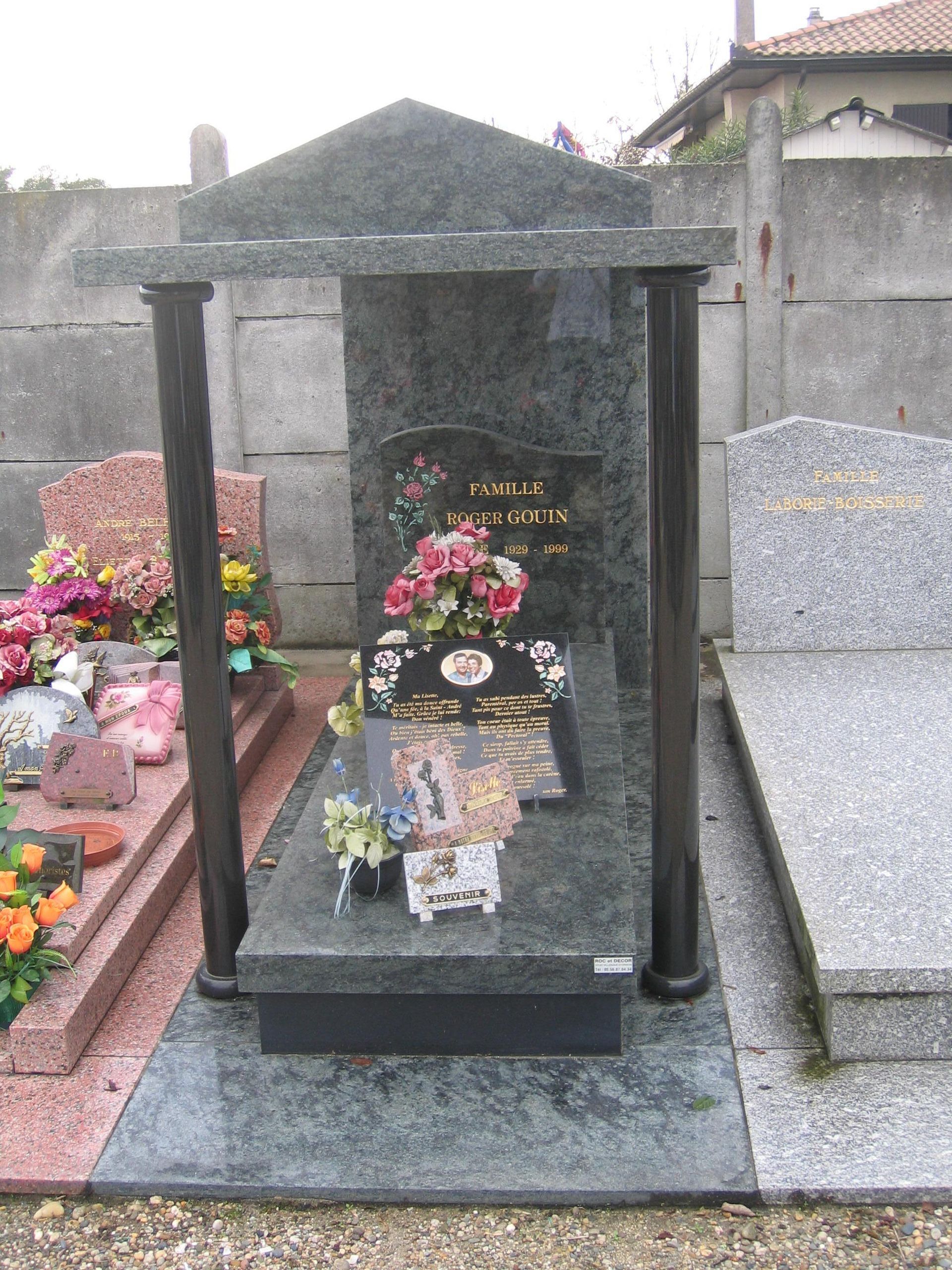 Pierre tombale couverte et décorée de plaques et fleurs