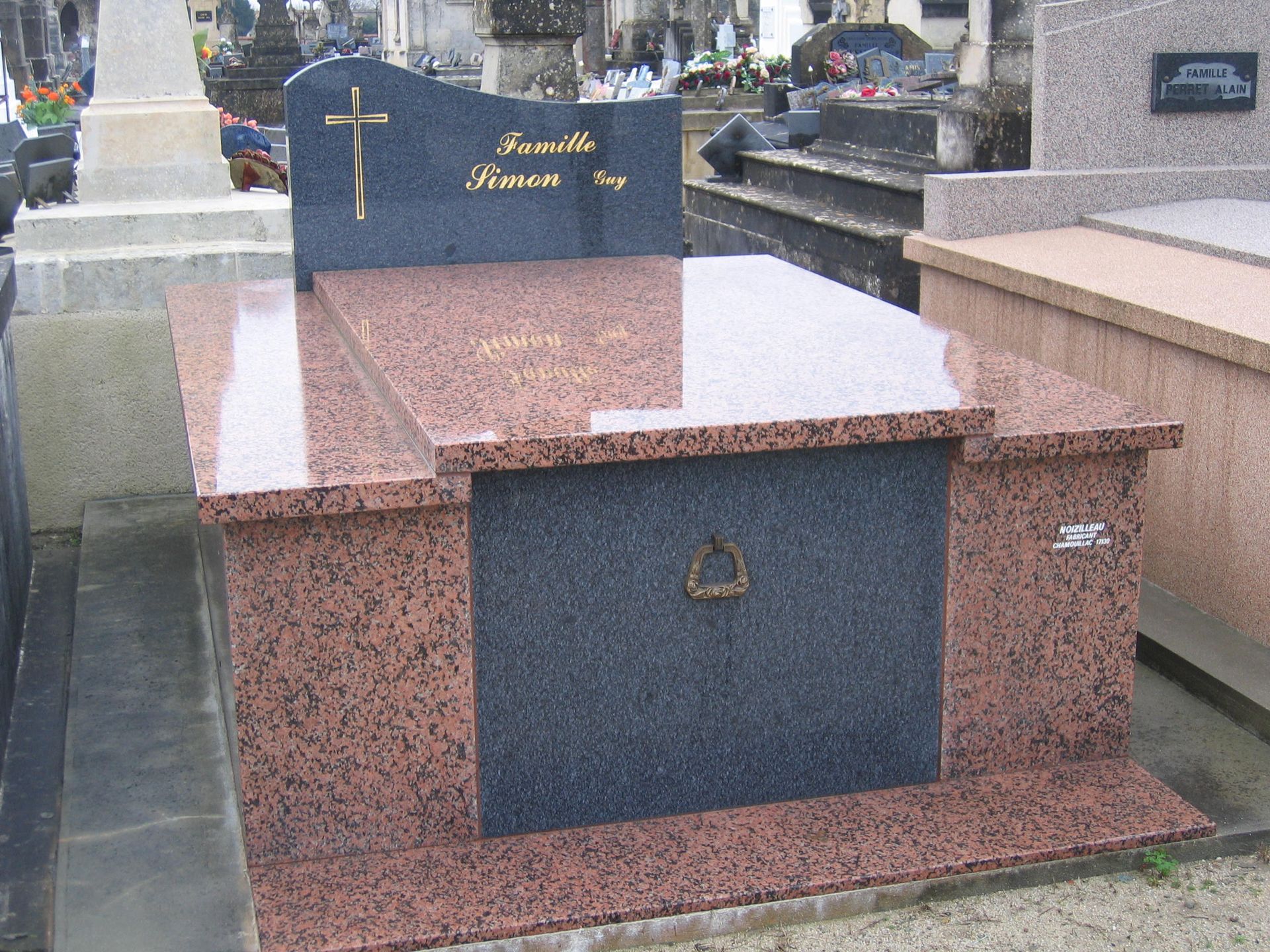 Pierre tombale en granit avec croix, inscription nominative et panneau central sombre.