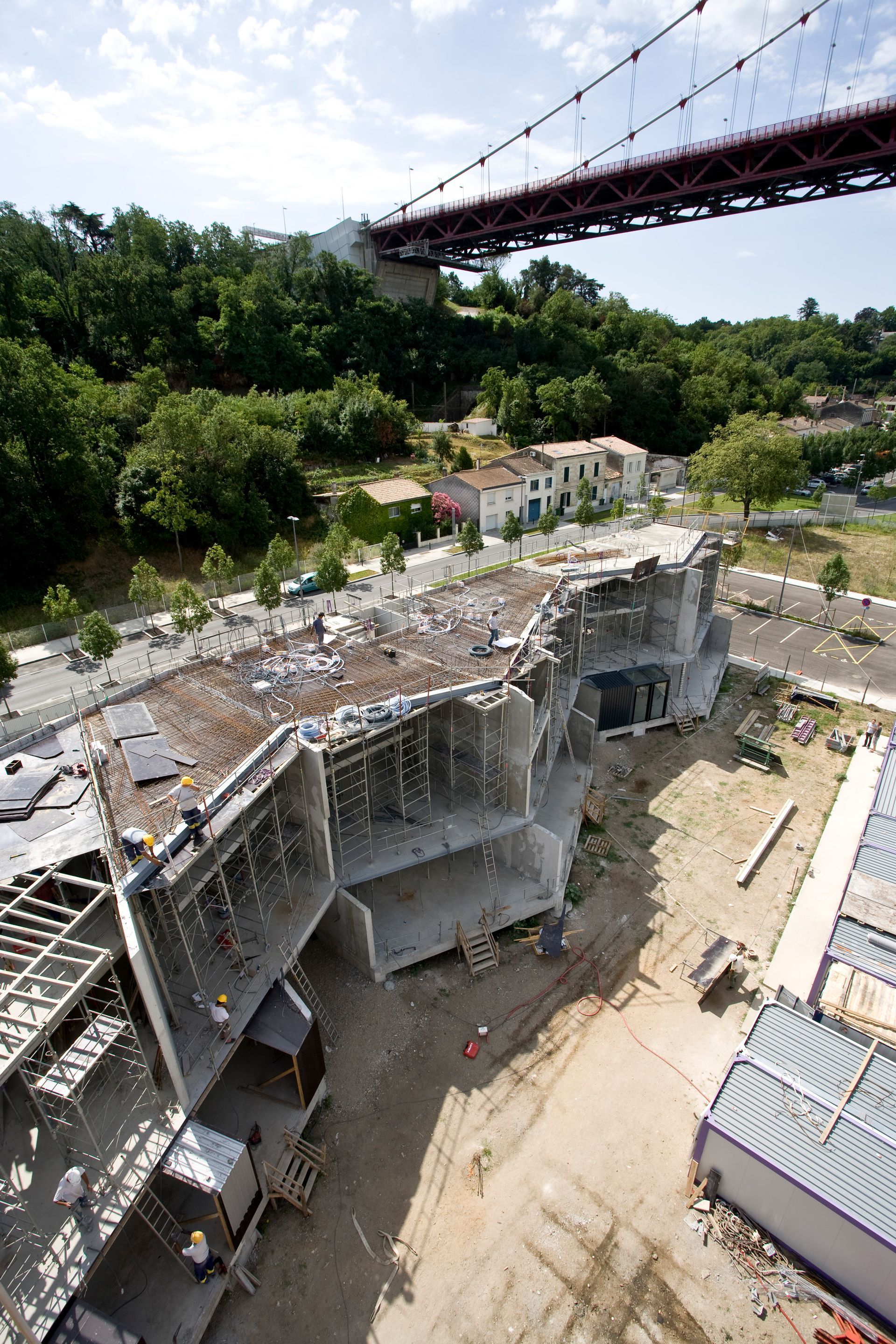 Chantier de construction avec structure en béton partiellement construite sous un pont.