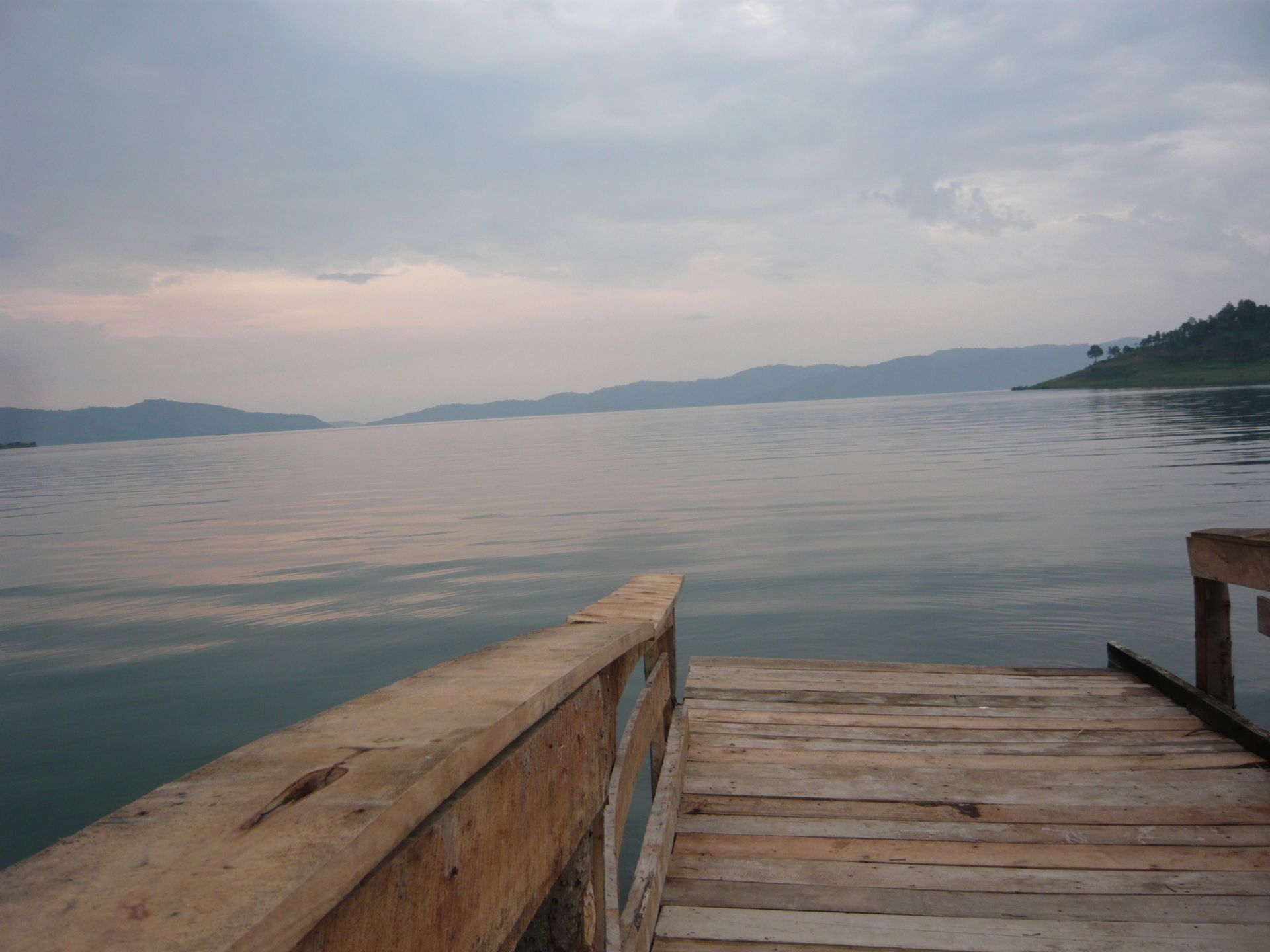 Intérieur d'un immeuble moderne avec de grandes fenêtres. On aperçoit un pont à travers celles-ci. Des chaises rouges entourent une table.