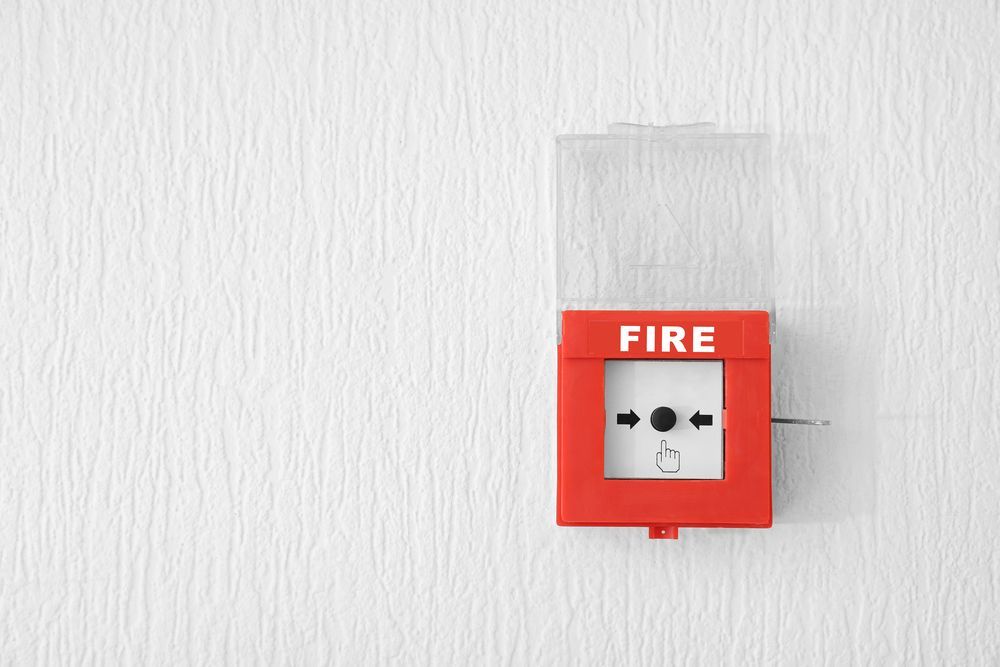 Una alarma de incendios roja está colgada en una pared blanca.