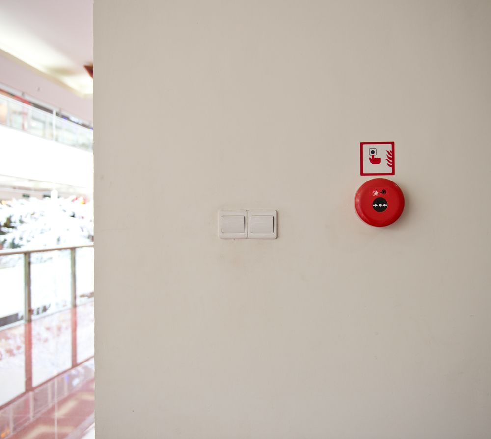 Una pared blanca con una alarma de incendios roja en ella