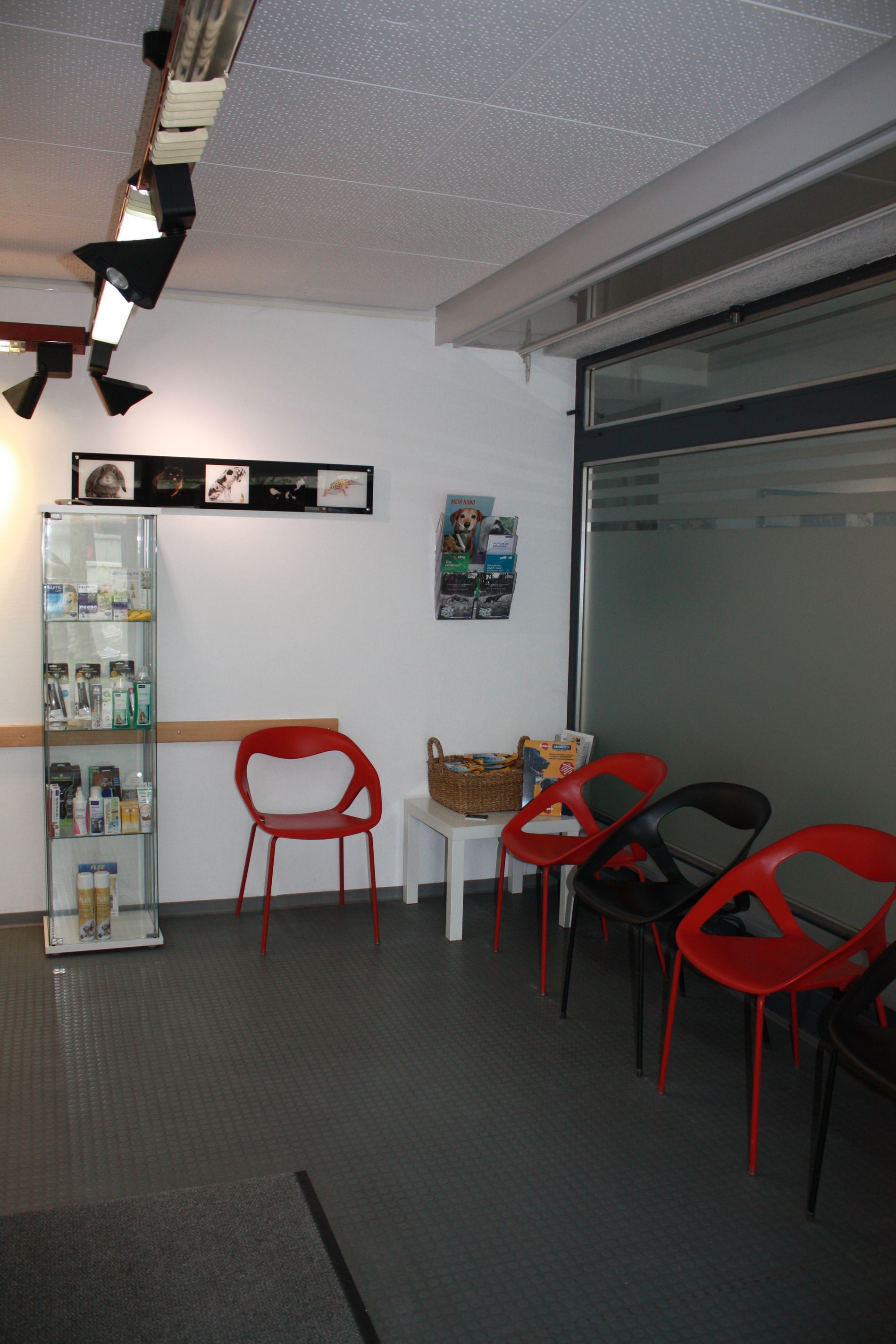 Ein Wartezimmer mit roten Stühlen und einer Vitrine