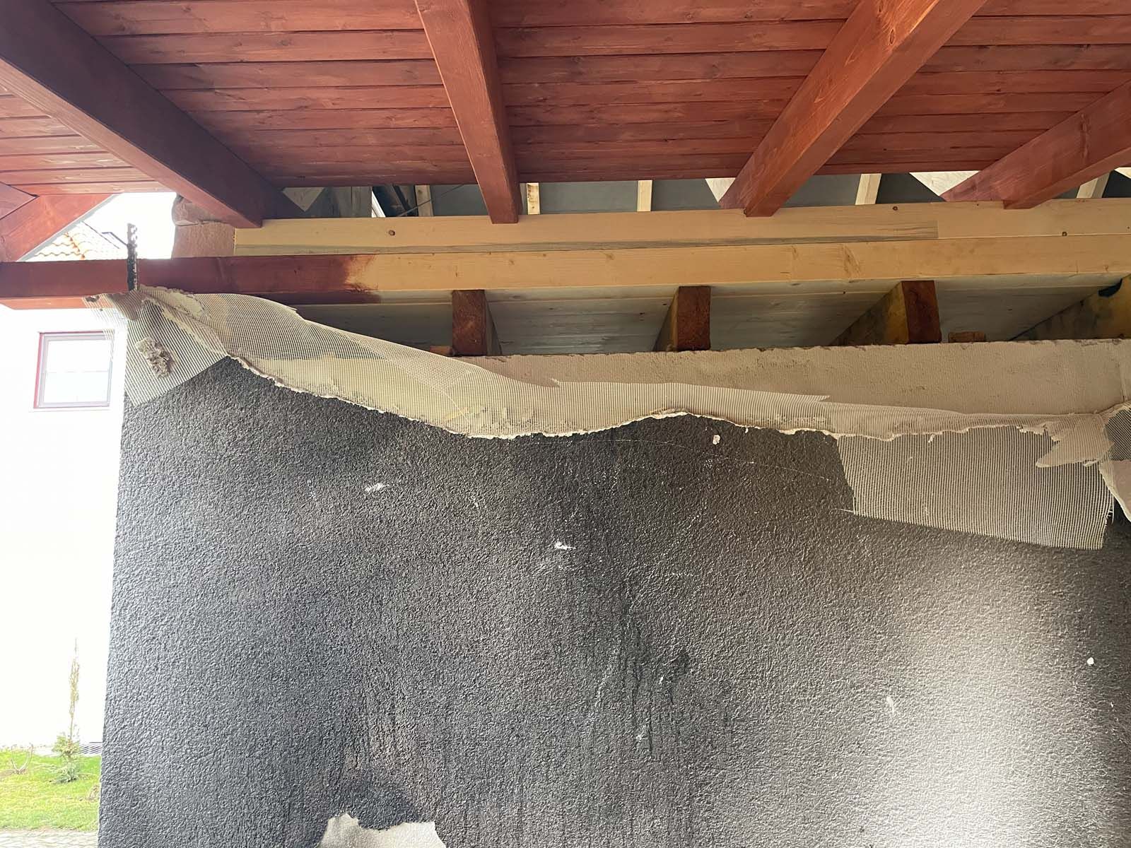 Ein Schwarm schwarzer Käfer bedeckt eine Mauer unter einem Holzdach, über das eine gestreifte Plane gespannt ist.