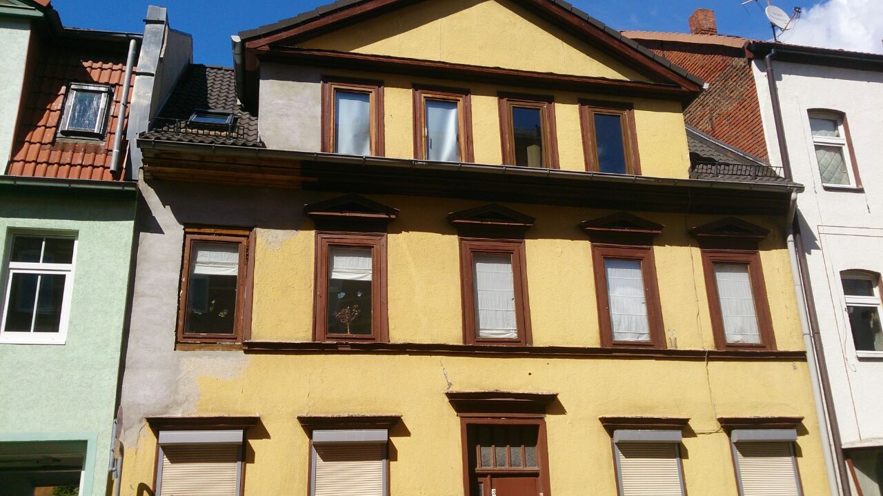 Farbenfrohe Reihe schmaler europäischer Häuser mit hohen Fenstern und schrägen Dächern im Sonnenlicht
