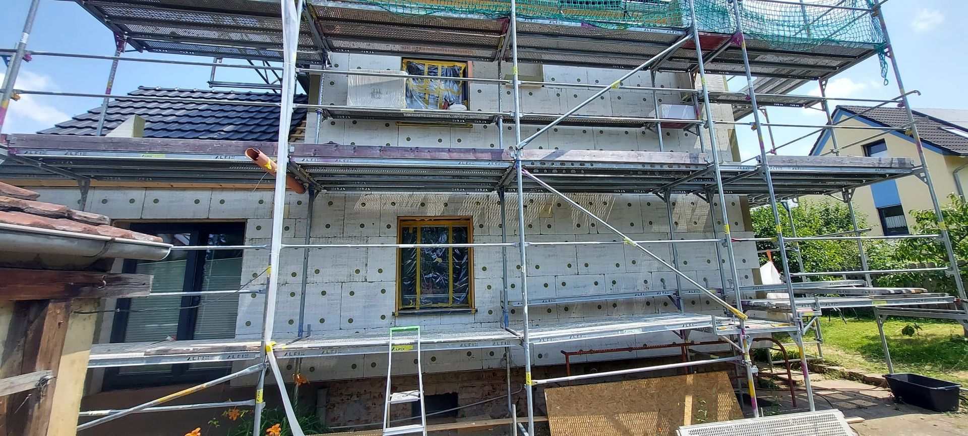 Haus wird renoviert, die Vorderfassade ist mit einem Gerüst und Schutznetzen versehen.