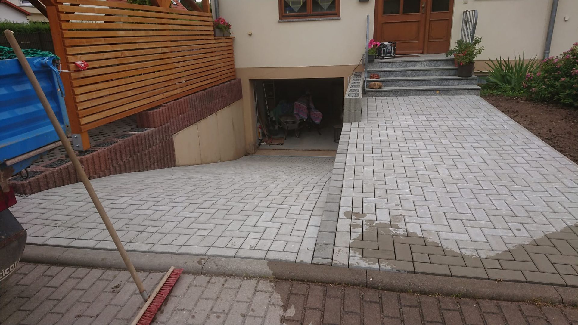 Eine mit Ziegelsteinen gepflasterte Auffahrt führt zum Hauseingang, mit Rampe und überdachtem Parkplatz unter der Veranda.
