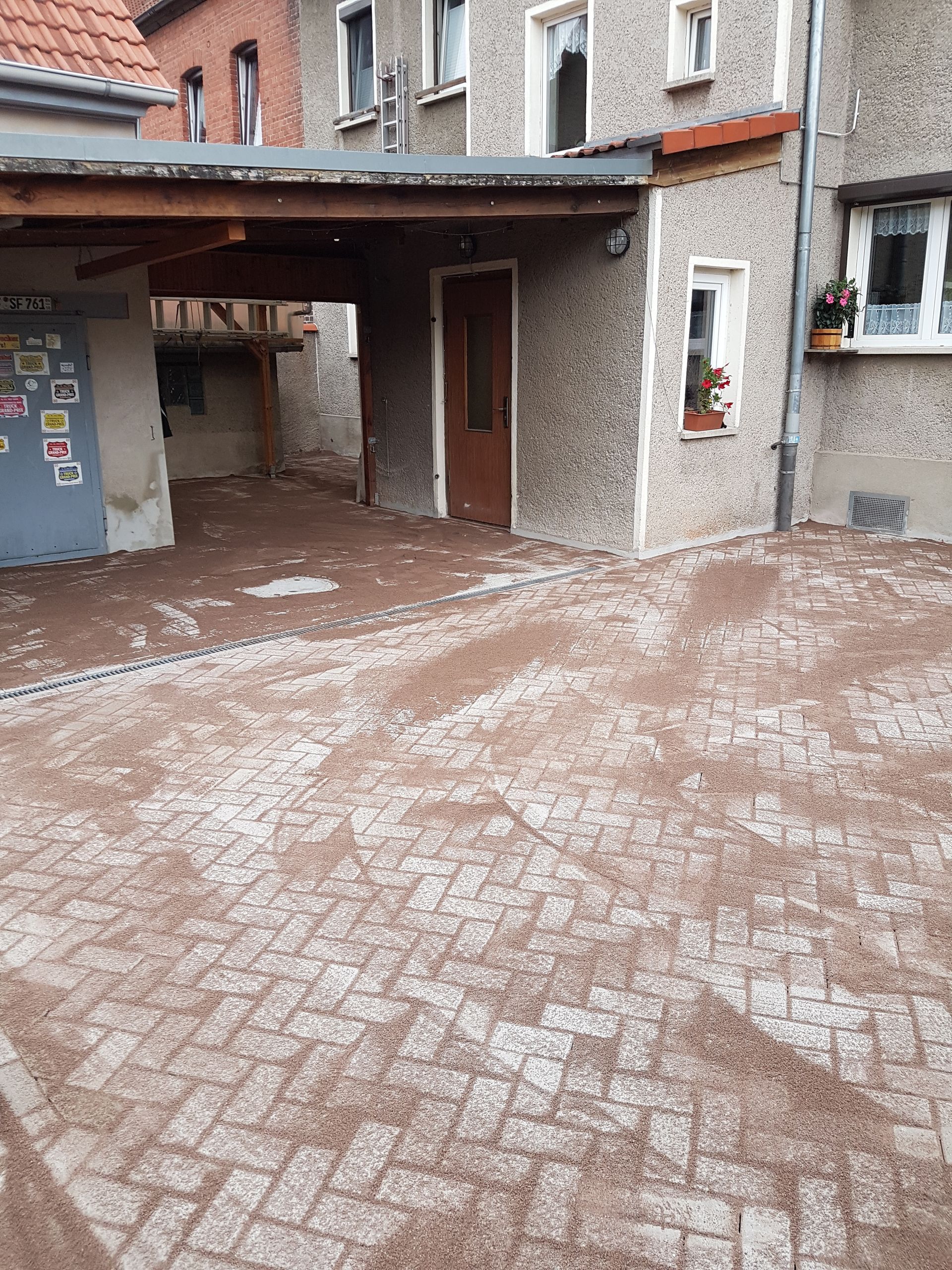 Schneebedeckter Backsteinhof mit überdachtem Eingang und einem Bogengang zwischen den Gebäuden
