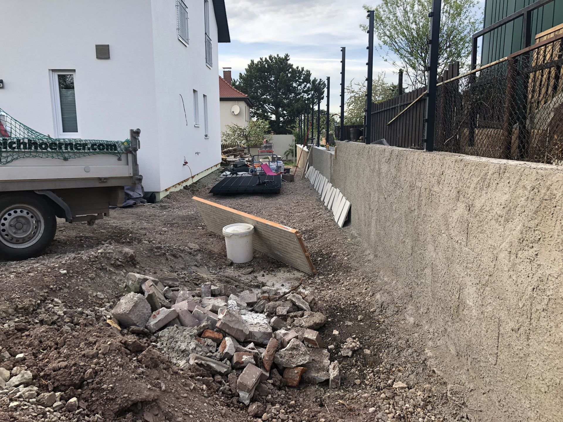Bauschutt lag verstreut in einer schmalen Gasse neben einem weißen Gebäude und einer hohen Mauer.