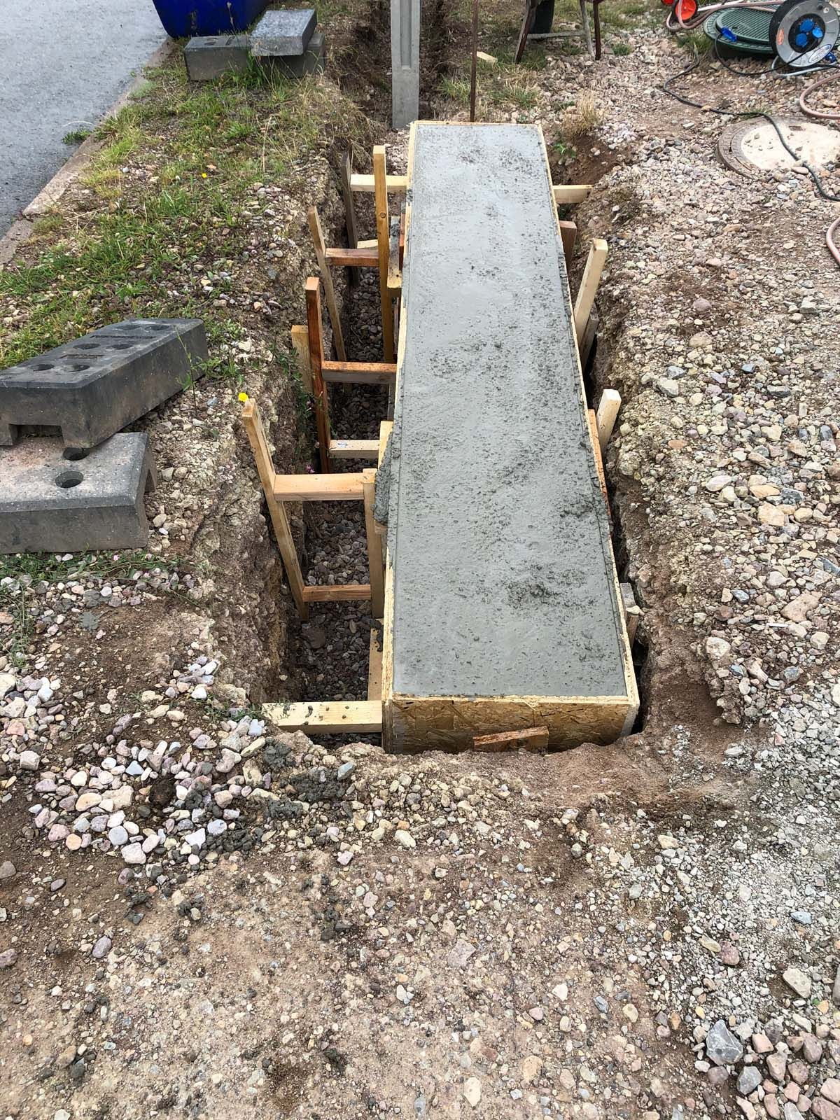 Betonplatte im Bau mit Holzstützen neben einem Kiesweg