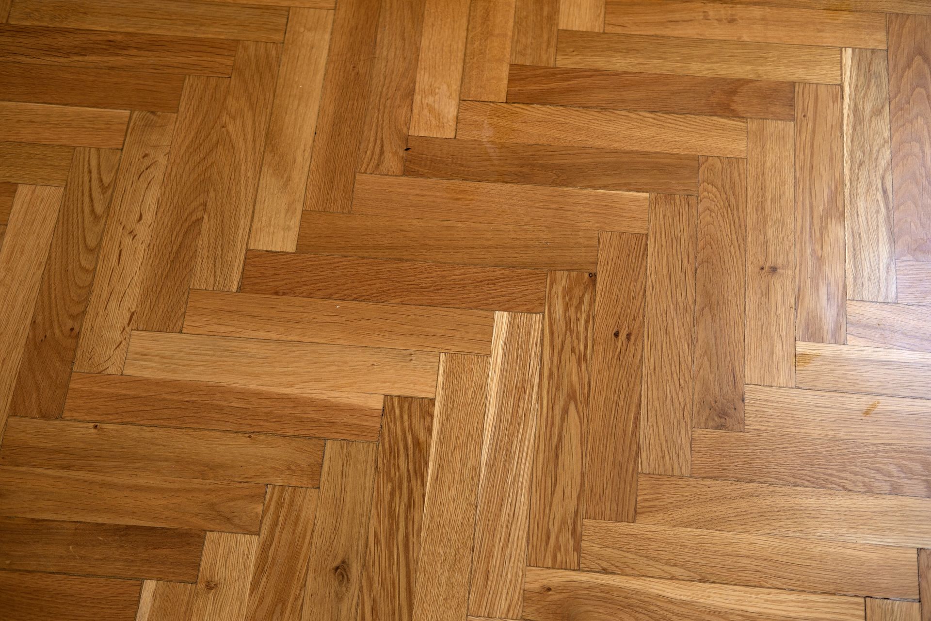 Gros plan sur un parquet en chêne clair posé selon un motif à chevrons classique.