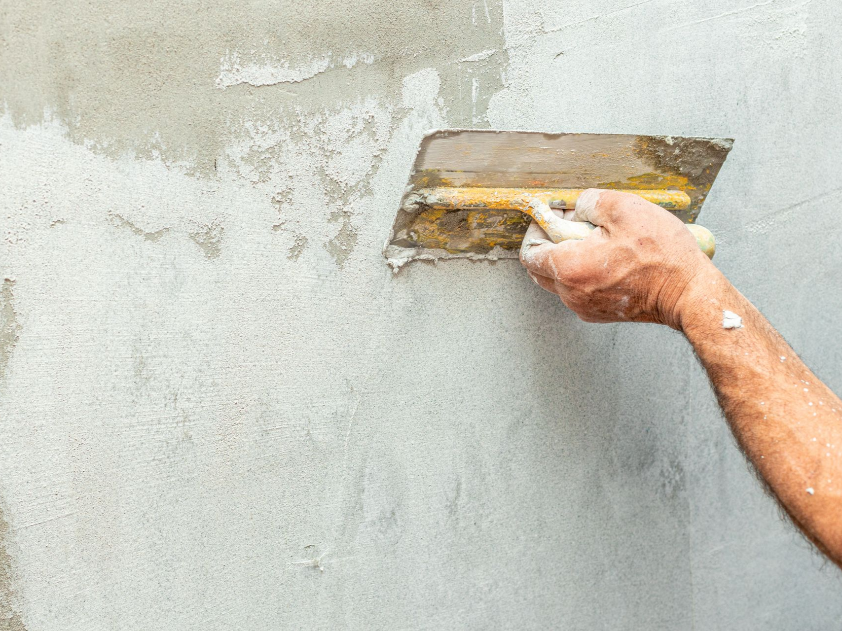 Gros plan sur une main masculine qui applique un enduit.