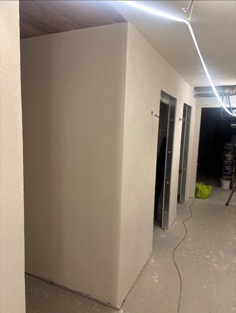 Intérieur avec murs et portes fraîchement enduits, travaux en cours.