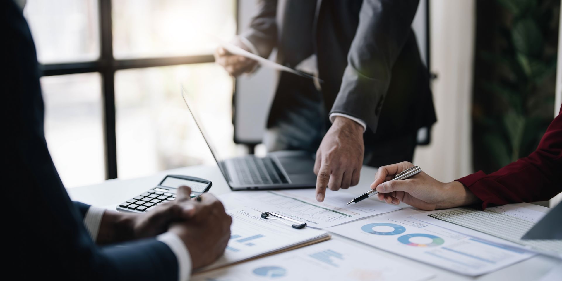 Los empresarios analizan informes financieros, señalando y discutiendo gráficos.