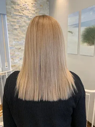 Frau mit glattem, hellblondem Haar; steht im Innenbereich.