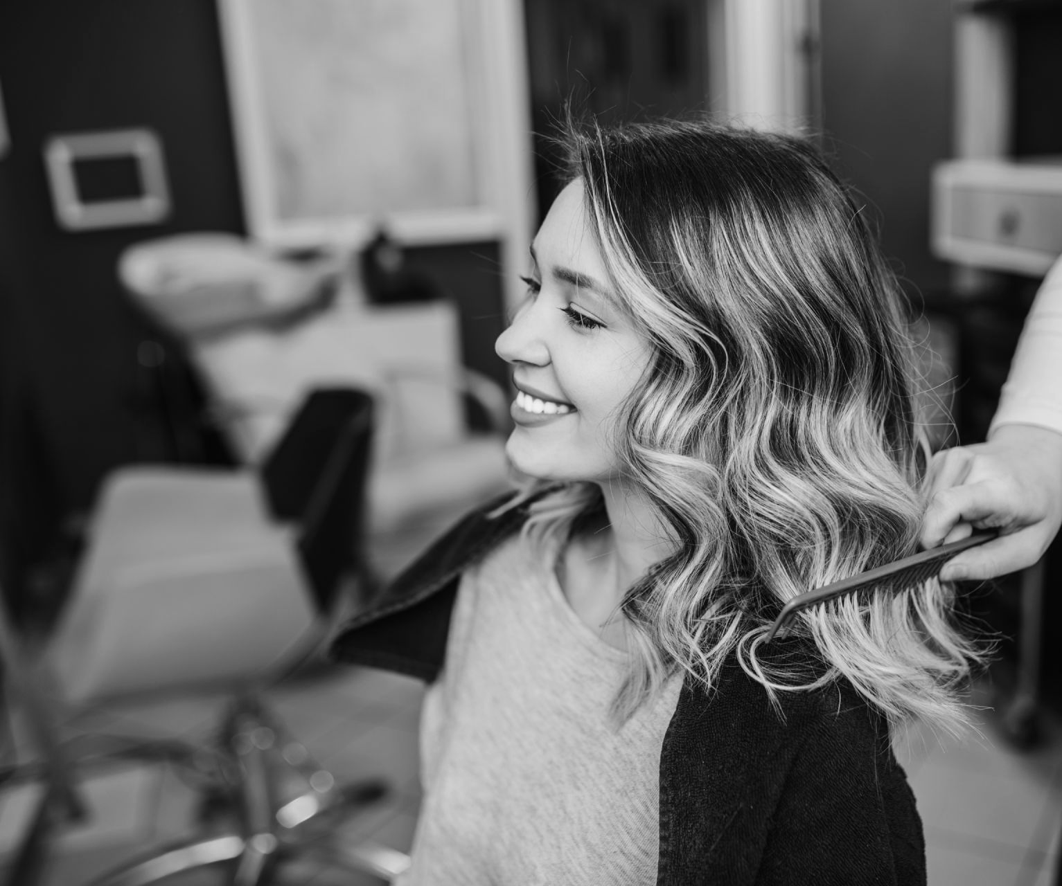 Eine Frau lässt sich in einem Salon von einem Friseur die Haare machen.