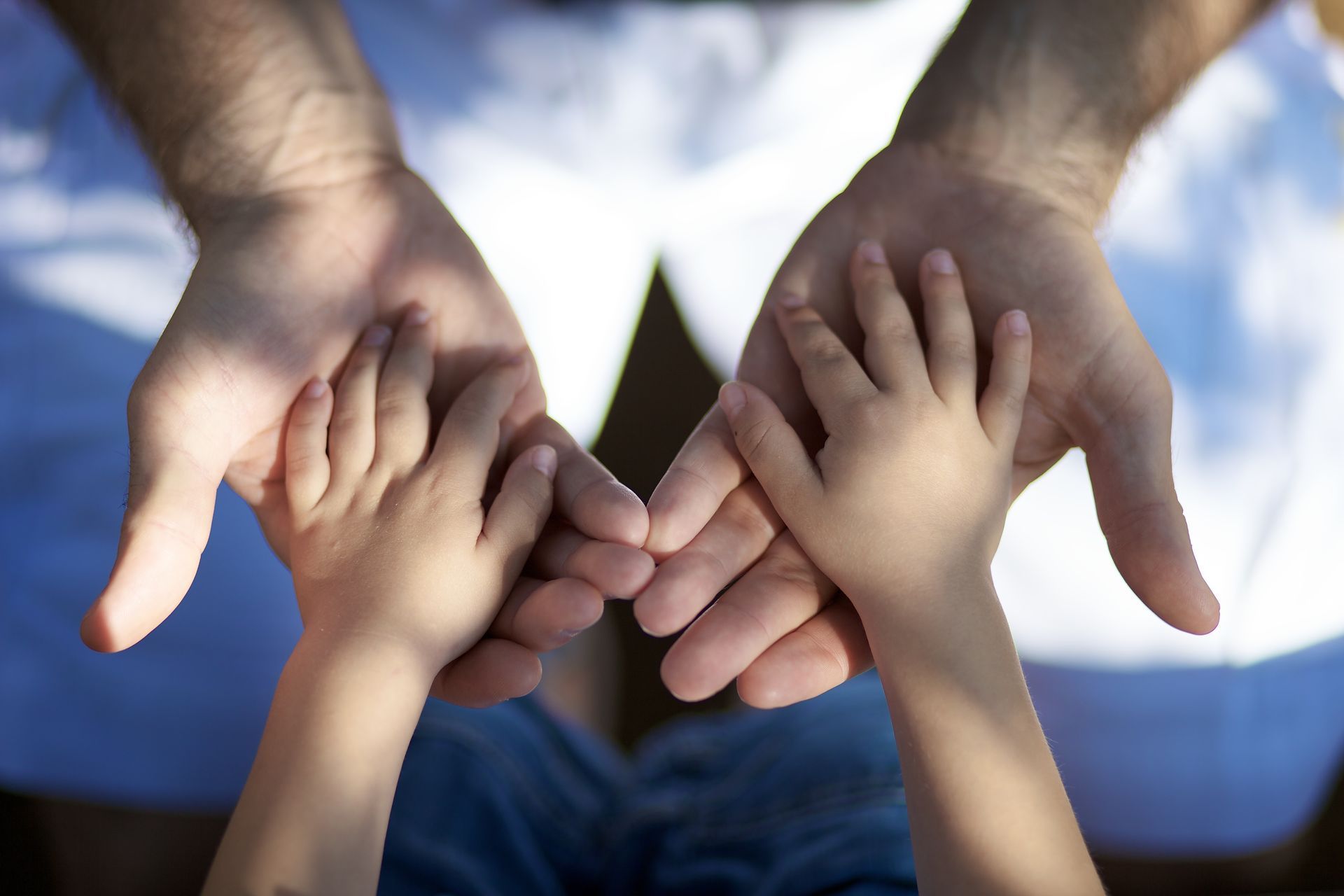 Mains d'enfants posées dans la paume de mains d'hommes