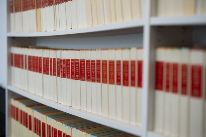 Regale mit weißen Büchern mit roten Etiketten in einer Bibliothek oder einem Archivbereich