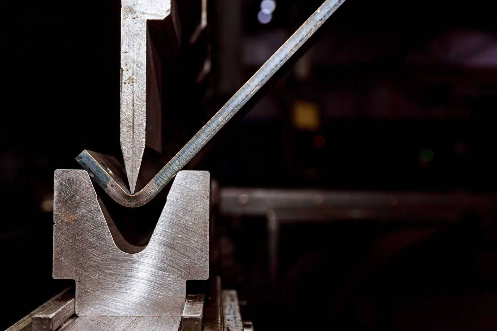 Una máquina está doblando una pieza de metal en una fábrica.