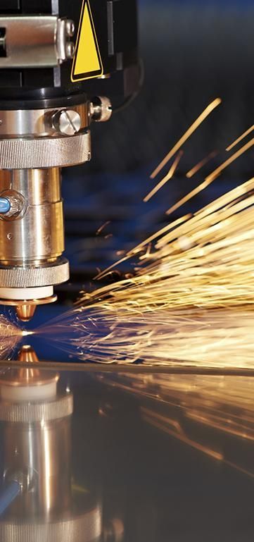 Una máquina está cortando un trozo de metal del que salen muchas chispas.