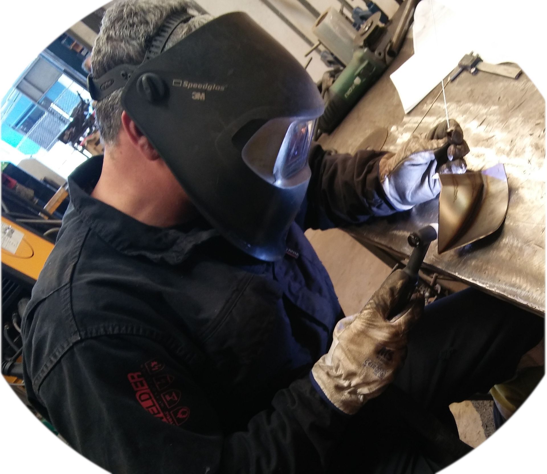 Un hombre que lleva un casco de soldadura está trabajando en una pieza de metal.
