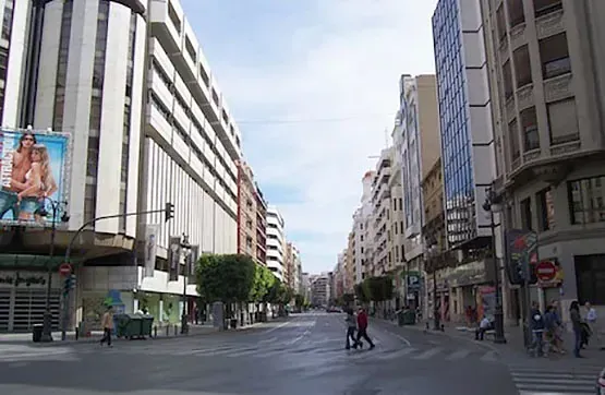 Una calle de la ciudad con muchos edificios y gente cruzando la calle.