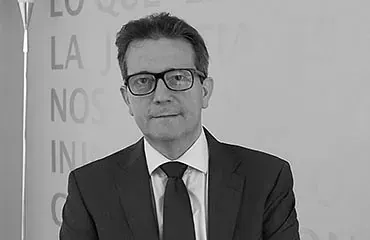 Un hombre con traje y corbata está de pie frente a una pizarra blanca.