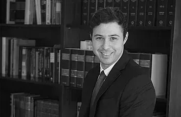 Un hombre con traje y corbata está de pie frente a una estantería.