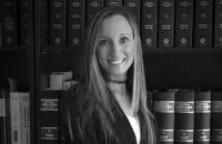 Una mujer sonríe delante de una estantería llena de libros.