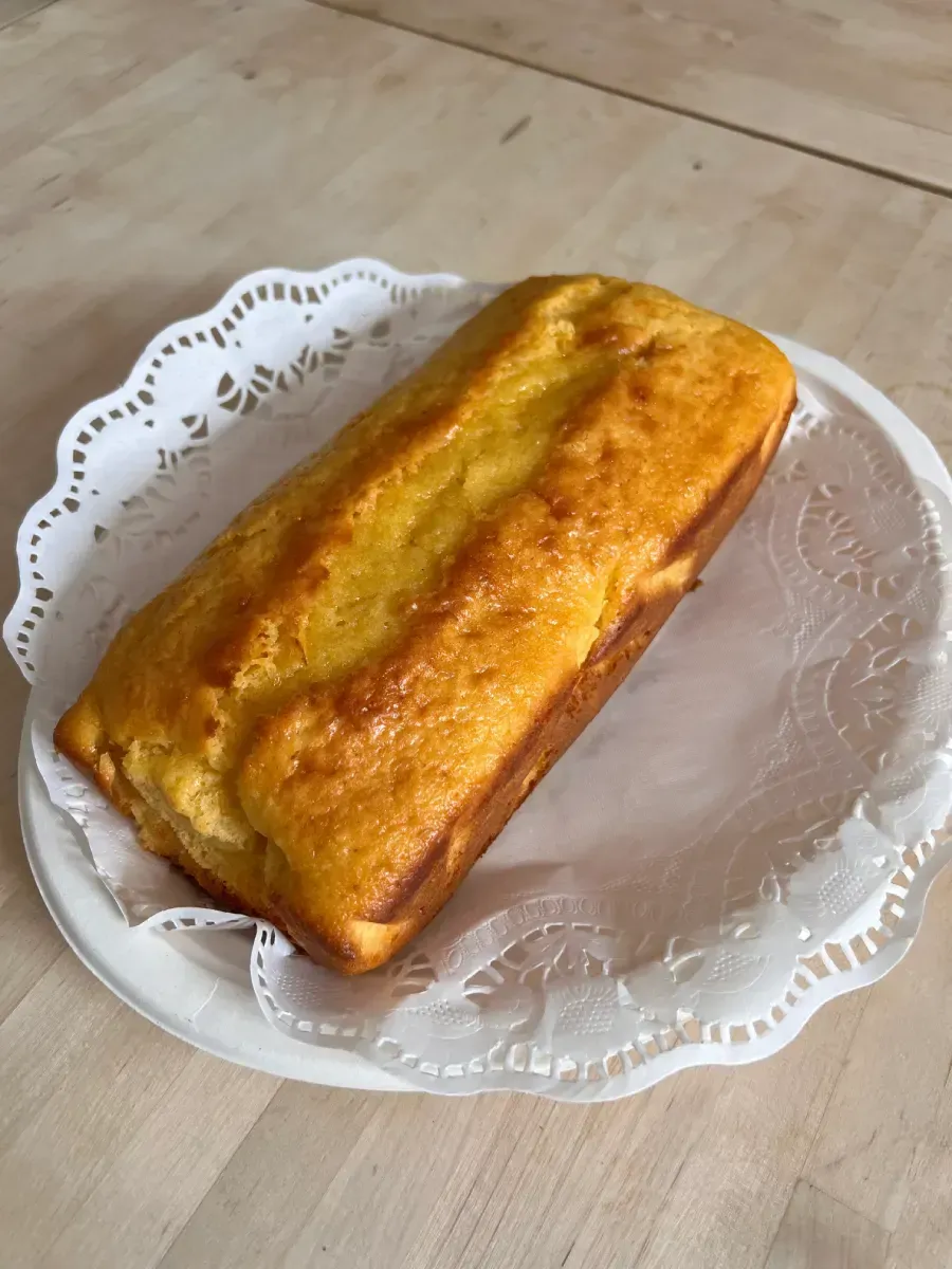 Bizcocho dorado sobre una blonda de papel blanca, colocado en un plato.