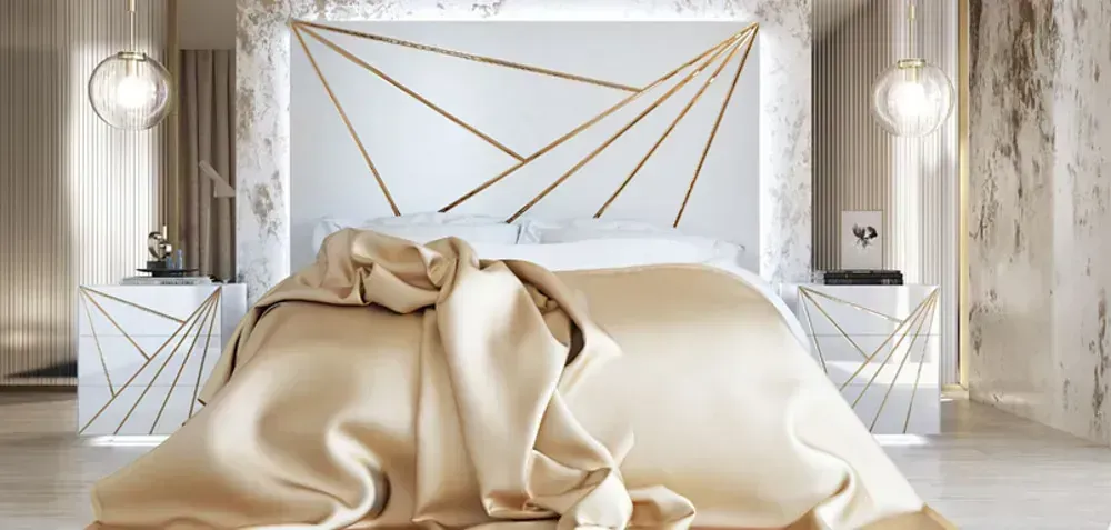 Dormitorio con cabecero y mesitas de noche con motivos geométricos en blanco y dorado, ropa de cama de color dorado suave y paredes de mármol.