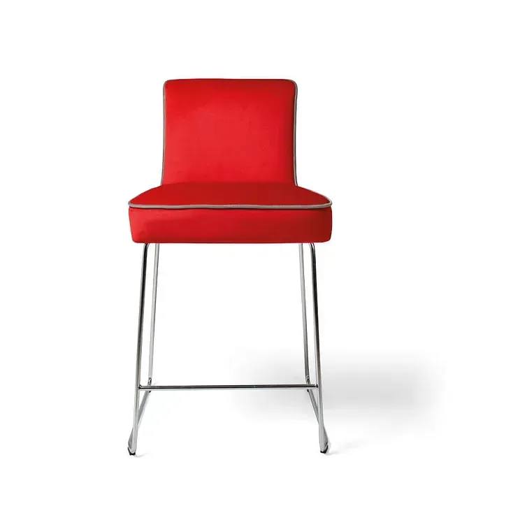 Un taburete de bar rojo con patas cromadas sobre un fondo blanco.